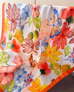 Detailed view of vibrant floral and butterfly printed satin silk scarf with orange hem