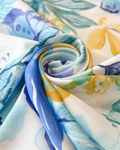Detailed close-up of smooth silk-like fabric with blue floral and butterfly print pattern
