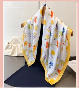 Detail of floral printed silk scarf with yellow borders hanging on a wooden hanger