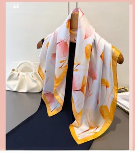 Détail d'un foulard en soie avec imprimé artistique orange-rose et ourlet jaune