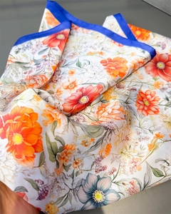 Detailed close-up of a floral silk scarf with vibrant orange flowers and royal blue borders