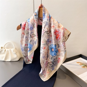 Elegant floral print silk scarf in champagne with large blue flowers on a wooden hanger