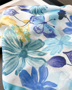 Detailed macro view of floral print on premium silky scarf with blue watercolor patterns