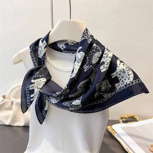 Close-up of retro elephant print silk scarf tied on a white halter neck top with pearls
