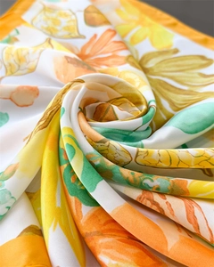 Detail showing the smooth silk texture and vibrant yellow floral print on the scarf