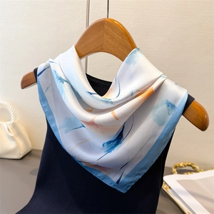 Détail d'un élégant foulard en soie aux motifs aquarelle bleu et orange sur un vêtement noir