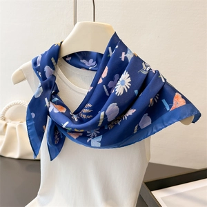 Detail of elegant navy floral silk scarf with daisy pattern draped on a white vest
