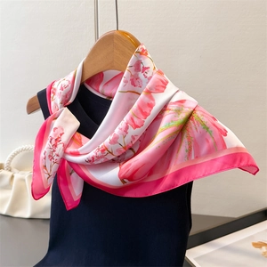 Detail of silk-like scarf with pink tulip floral print on elegant wooden hanger