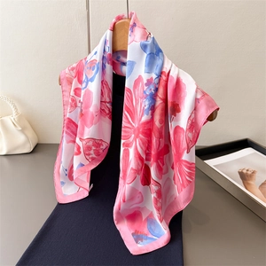 Elegant floral silk-feel square scarf with pink blooms hung on a wooden hanger