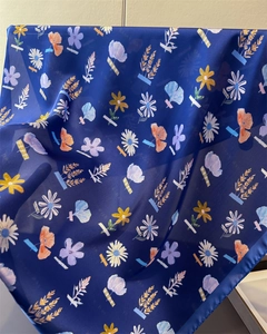 Detailed view of dark blue floral silk scarf with vibrant daisy and poppy print textures