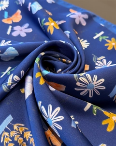 Detailed macro shot of soft navy blue silk satin scarf with elegant floral daisy patterns