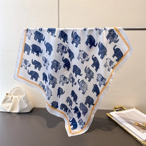 Detail of silk square scarf featuring blue elephant prints and yellow chain border designs