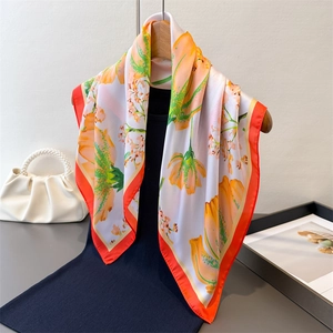 Floral print silk scarf with orange flower pattern and red border on navy dress