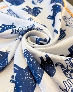 Detailed shot of satin scarf with abstract blue bird print and orange LOOO border
