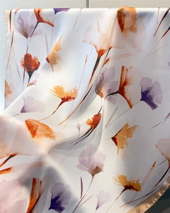 Gros plan d'un foulard en soie avec imprimé floral orange et bordure délicate