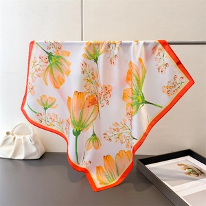 Detailed texture of white silk scarf with orange tulip patterns and vibrant orange border