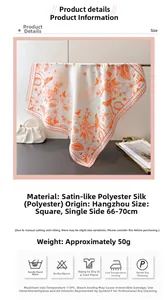 Detail of silk-like satin square scarf with orange floral and bird prints and soft texture