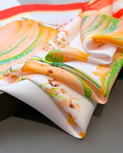 Macro detail of high-quality floral silk scarf showing satin texture and red hem edges