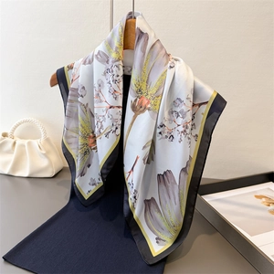 Floral print silk scarf with purple petals and black borders on an elegant hanger