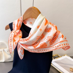 Close-up of elegant floral and butterfly print silk scarf on a hanger with pearls