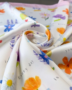 Detail of silk-satin scarf featuring floral prints and pink borders with smooth texture