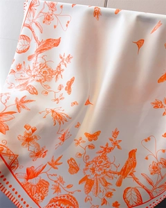 Detail of silk-like scarf featuring orange Toile de Jouy floral and bird prints