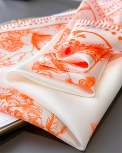 Close-up of elegant silk scarf with orange floral patterns and satin smooth texture