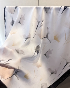 Détail d'un foulard en soie blanche avec motifs floraux à l'encre et bordure noire