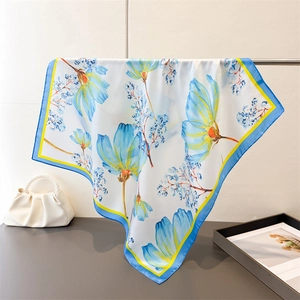 Detail of floral silk scarf showing light blue flowers and smooth satin texture