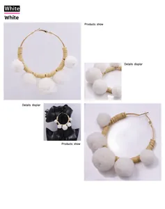 Detail of bohemian gold hoop earrings with white faux fur pom-poms and khaki beads