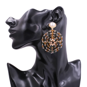Detail of bohemian round earrings with green rhinestones and a large white pearl stud