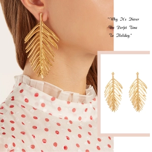 Detail view of large gold palm leaf earrings on model and a white background