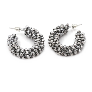 Detail of woven C-shaped earrings with multifaceted metallic beads and silver posts
