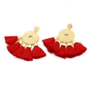Detailed macro view of bohemian gold round metal motifs and vibrant red silk tassels