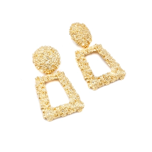 Detailed macro shot of chunky gold geometric earrings with textured lava relief surface