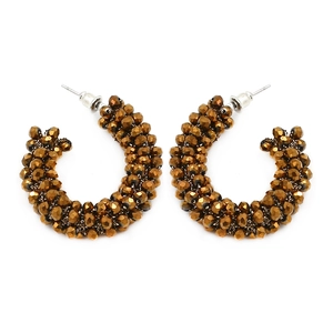 Detail of C-shaped earrings with woven brown faceted crystal beads on white background