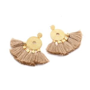 Detail of bohemian gold textured stud earrings with elegant beige silk tassels