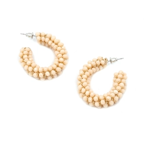 Detailed view of bohemian C-shaped hoop earrings with woven light beige crystal beads