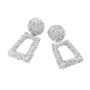 Close-up of silver long geometric earrings featuring heavy textured relief and floral patterns