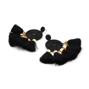 Close-up of black bohemian tassel earrings with golden hardware on a white background