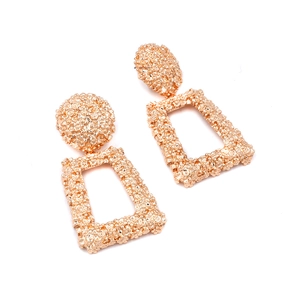 Detail of rose gold geometric earrings with intricate floral relief and metallic texture