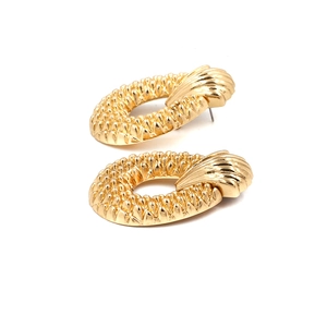 Detail of oval golden metal earrings with textured beads and sunburst shell pattern