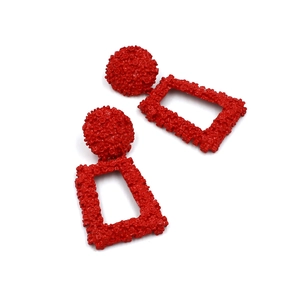 Detailed view of red geometric earrings featuring textured floral relief and rectangle drop