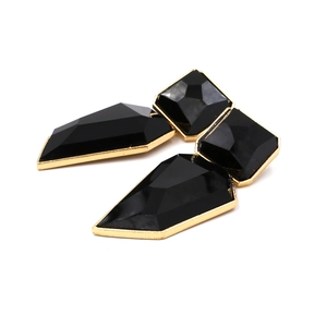 Detail of geometric resin earrings with black stones and gold metal frame inlay