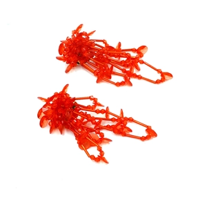 Dettaglio di orecchini di perline arancioni con fiori di cristallo e lunghe frange