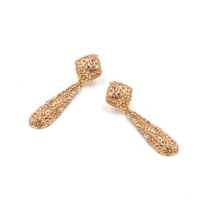 Gros plan de boucles d'oreilles pendantes dorées avec pavage de cristaux étincelants