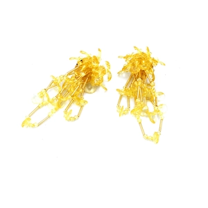 Dettaglio macro di orecchini a nappa con cristalli gialli e lunghe frange dorate