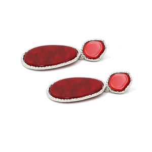 Detail of teardrop resin earrings with dark red stones and textured silver metal frames