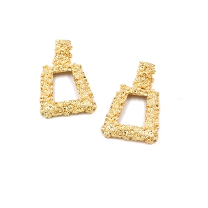 Detailed macro view of gold geometric earrings with vintage embossed textured finish