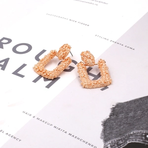 Detail of rose gold trapezoid earrings with irregular hammered texture and metallic finish